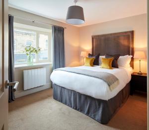 a bedroom with a large bed with yellow pillows at Rooms by Bistrot Pierre at The Crescent Inn in Ilkley