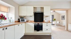 a kitchen with white cabinets and a stove top oven at Rooms by Bistrot Pierre at The Crescent Inn in Ilkley