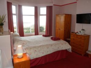 Schlafzimmer mit einem Bett, einer Kommode und einem Fenster in der Unterkunft Wavecrest Lodge in Fleetwood