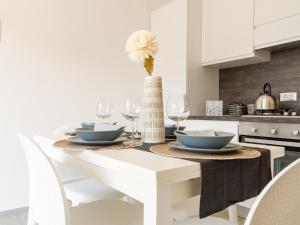 eine weiße Küche mit einem Tisch mit einer Vase mit einer Blume in der Unterkunft FCO Luxury Apartments in Fiumicino