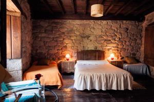 a bedroom with two beds and a stone wall at Reitoral de Chandrexa in Parada del Sil