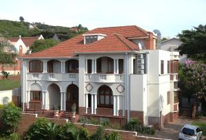 une maison blanche avec un toit rouge dans l'établissement Saint James on Venice, à Durban