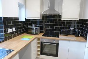 a kitchen with white cabinets and black tiles on the wall at Brookdale Lodge in Telford