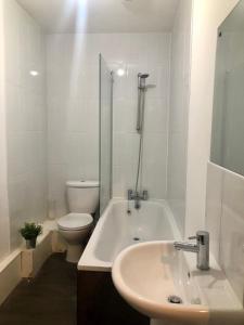 a white bathroom with a toilet and a sink at Smart central apartment, 5 mins from centre in Cardiff