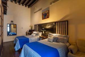 a hotel room with two beds and a mirror at Hotel Mansion Iturbe in Pátzcuaro