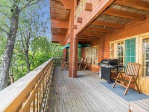 a wooden deck with a grill and chairs on it at Holiday Home Koivuranta by Interhome in Kylmälä