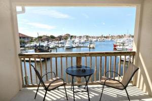 uma varanda com duas cadeiras, uma mesa e barcos em Inn at Camachee Harbor View 22 em Saint Augustine
