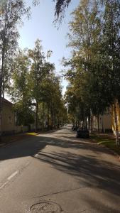 an empty street with trees and a car parked on the road at Apartment Lintu in Mikkeli