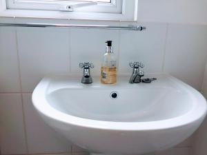 un fregadero blanco con una botella de jabón. en Warwick House, 5 bedrooms, 9 beds, parking, garden en Coventry