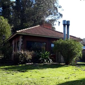une petite maison avec une cour en gazon devant elle dans l'établissement Bosque Peralta Ramos. Zorzales del Bosque, à Mar del Plata