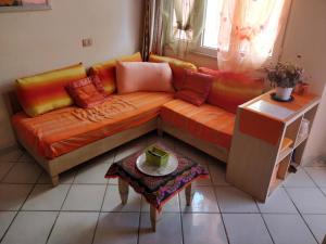 an orange couch in a living room with a table at Sardegna per 5 in Isola Rossa