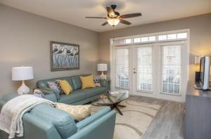 een woonkamer met een blauwe bank en een plafondventilator bij Seaside at Anastasia C202 in St. Augustine