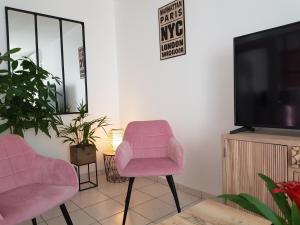 sala de estar con 2 sillas rosas y TV en Le Pompidou T2 pour 2 à 4 pers avec parking privé & balcon Place Ney en Angers