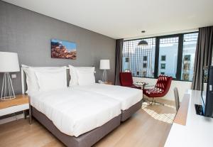 a bedroom with a large white bed and a desk at Pestana Cidadela Cascais - Pousada & Art District in Cascais