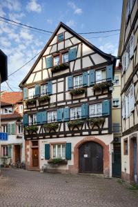 un bâtiment à colombages avec des fenêtres et des plantes bleues dans l'établissement Historisches Gästehaus Au Faucon, à Wissembourg