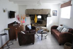 ル・コンケにあるGîtes Le Bout du Mondeのリビングルーム(ソファ、椅子、暖炉付)