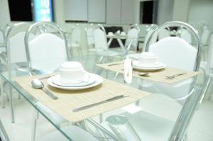 a table with white plates and utensils on it at Gran Norte Hotel - Salinas - MG in Salinas