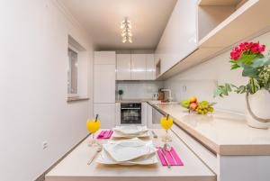 a white kitchen with a table with glasses of orange juice at Apartment M&M Klimno in Klimno +21 photos