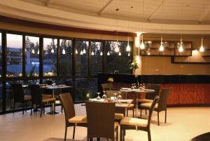 un restaurant avec des tables, des chaises et des fenêtres dans l'établissement Tara Mantra Cha-Am Resort, à Cha Am