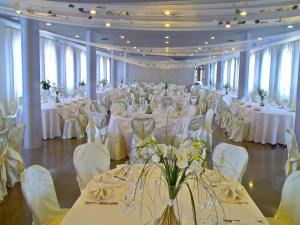 チッタデッラにあるHotel Filandaの白いテーブルと白い椅子が備わる宴会場