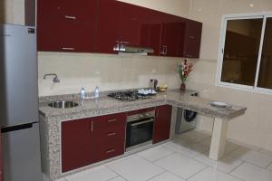 a kitchen with red cabinets and a counter top at Residence Achomoukhe in Laayoune