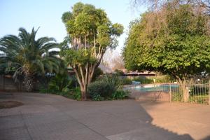 um jardim com uma piscina e árvores e uma cerca em Green Grove Villa em Centurion