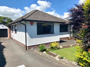 a small white house with a driveway at Glenwell House in Newtownabbey