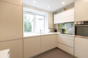 una cocina con armarios blancos y una ventana en City center Gauja apartment, en Valmiera