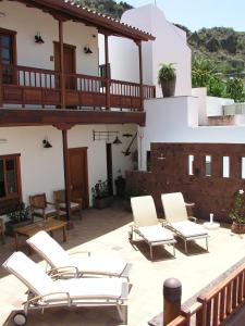 un patio con sillas blancas y una casa en Hotel Rural Fonda de la Tea THE BEST LOCATION AND THE BEST VIEWS, en Tejeda