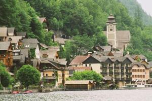 een stad met een klokkentoren aan de kant van een rivier bij Bräugasthof Hallstatt in Hallstatt