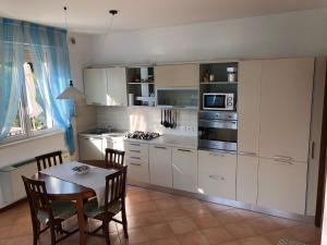 eine Küche mit weißen Schränken und einem Tisch mit Stühlen in der Unterkunft Casa Alice Garda in Garda