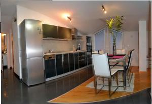 a kitchen with a table and a stainless steel refrigerator at Comfort Deluxe Kosmos Apartments in Ohrid