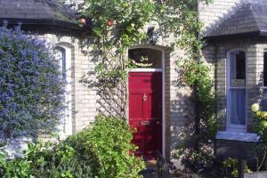 una puerta roja en una casa de ladrillo con arbustos en Number 34 Bed and Breakfast York, en York