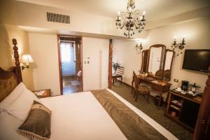 
a hotel room with a bed, table, chairs and a mirror at Aranwa Cusco Boutique Hotel in Cusco
