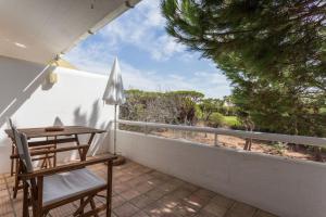 een terras met een tafel, stoelen en een parasol bij 1Bed Apart Quinta do Lago in Almancil
