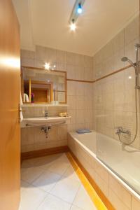 a bathroom with a tub and a sink and a shower at Pension Koch in Uttendorf