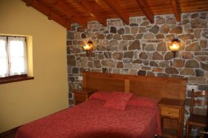 um quarto com uma cama e uma parede de pedra em La Casona De Entralgo em Pola de Laviana