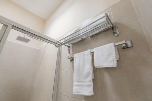 y baño con ducha y toallas blancas. en Habitaciones Lucero 2 en Santa María del Oro