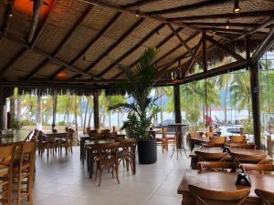 a restaurant with wooden tables and chairs and a lot of windows at Ilha Flat Apto 3207 in Ilhabela