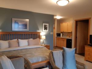 a bedroom with a large bed and a kitchen at Reef Point Oceanfront Bed and Breakfast in Ucluelet