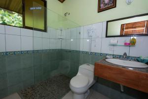 a bathroom with a toilet a sink and a mirror at Hotel Sunshine Caribe in Puerto Viejo