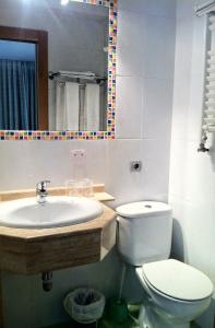 a bathroom with a sink and a toilet and a mirror at Hostal Del Carmen in Santander