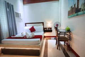 een slaapkamer met een bed, een tafel en een stoel bij Elizabeth Hotel - Naga in Pili