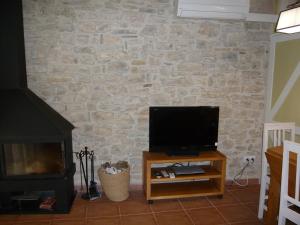a television on a stand in front of a stone wall at Cal Josep in Portell