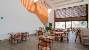 Un restaurante con mesas y sillas y un gran ventanal. en Miyana Suites, en Ciudad de México