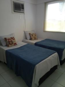 Mangaratiba Porto Real Suíte في مانغاراتيبا: سريرين في غرفة ذات أغطية زرقاء ونافذة