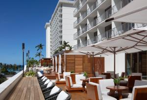 een hotelpatio met stoelen, tafels en parasols bij 'Alohilani Resort Waikiki Beach in Honolulu