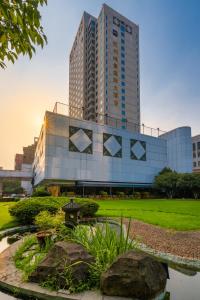 um edifício alto com um parque em frente em Grand Metropark Hotel Hangzhou em Hangzhou