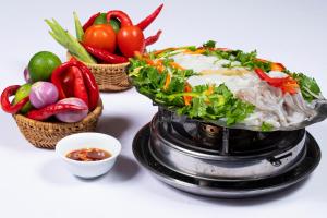 a plate of food with vegetables and a bowl of dipping sauce at Hon Rom Central Beach Resort in Mui Ne