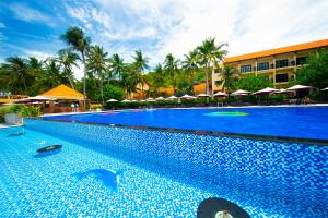 a large blue swimming pool with palm trees and a building at Hon Rom Central Beach Resort in Mui Ne